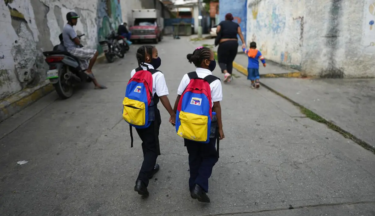 Anak-anak berjalan kaki ke sekolah pada hari pertama kembali ke kelas tatap muka sejak dimulainya pembatasan pandemi COVID-19 di Caracas, Venezuela, 25 Oktober 2021. (AP Photo/Ariana Cubillos)