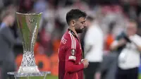 Bruno Fernandes berjalan melewati trofi Liga Europa&nbsp;usai laga Tottenham vs Manchester United di San Mames,&nbsp;Kamis (22/5/2025). (AP Photo/Bernat Armangue)