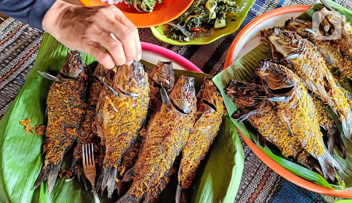 Hasil ikan mas yang telah diasapkan menggunakan kayu bakar di Setu Tujuh Muara Sawangan, Depok, Minggu (19/06/2022). Untuk dapat menikmati ikan asap, pengunjung harus memesan 1-2 hari sebelum dihidangkan karena proses pengasapan ikan yang memakan waktu sekitar 7 jam. (Liputan6.com/Fery Pradolo)
