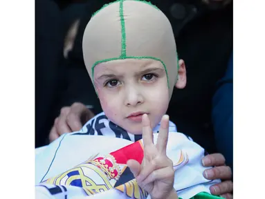 Ahmed Dawabsha adalah bocah berusa 5 tahun yang selamat dari bom di Palestina mengenakan bendera Real Madrid saat tiba di Bandara Adolfo Suarez, Madrid, Rabu (16/3/2016).  (AFP/Curto De La Torre)