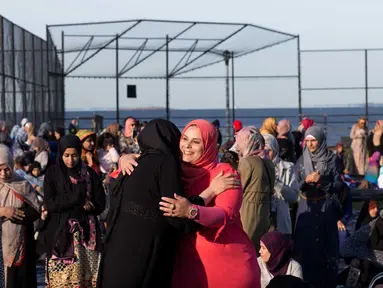 Wanita muslim saling berpelukan saat mereka bersiap melaksanakan salat Idul Adha di Taman Bensonhurst di wilayah Brooklyn di New York (1/9). Umat Muslim di seluruh dunia merayakan Hari RayaIdul Adha. (AP Photo / Mark Lennihan)