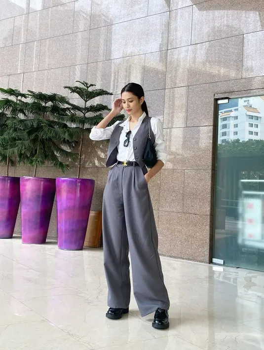 OOTD chic dari Mikha Tambayong. Ia mengenakan kemeja putih lengan panjang, ditumpuk dengan vest hitam dari kulit, kemudian dipadu dengan celana panjang abu-abu, diberi sentuhan belt hitam yang manis, dan loafer hitam. [Foto: Instagram/miktambayong]