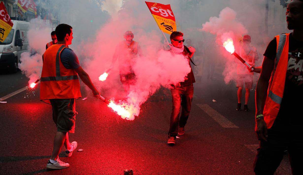 Pekerja kereta api memegang flare saat melakukan demonstrasi di Paris, Prancis (23/5). Mereka memprotes kebijakan pemerintah terkait pemangkasan 120.000 pekerjaan pada 2022. (AP/Francois Mori)