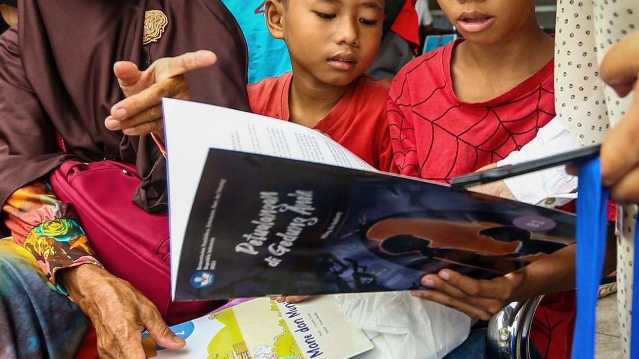 Tampak wajah ceria dari anak-anak yang hendak mudik saat membaca buku yang diberikan gratis oleh Badan Bahasa Kemendikbudristek di Teriminal Kalideres. Foto: Liputan6.com / Angga Yuniar