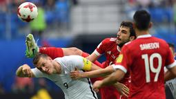 Aksi bek Rusia, Georgiy Dzhikiya (tengah) menghalau bola dari sundulan pemain Selandia Baru, Chris Wood pada laga perdana Piala Konfederasi 2017 grup A di Krestovsky Stadium, Saint-Petersburg, (17/6/2017).  (AFP/Kirill Kudryavtsev)