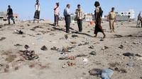 Sejumlah orang berkumpul di lokasi bom bunuh diri yang menyasar sebuah pangkalan militer kota Aden, Yaman, Minggu (18/12). Seorang anggota militer menyebut pelaku membaur di antara para tentara di pangkalan al-Solba. (SALEH AL-OBEIDI/AFP)