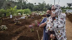Seorang ibu berkabung dengan putranya saat pemakaman ibunya di pemakaman Mulyaharja untuk korban virus corona Covid-19, di Bogor, Jawa Barat (8/7/2021). Menurut data LaporCovid-19 sejak Juni terdapat 311 pasien Covid-19 yang meninggal saat menjalani isolasi mandiri. (AFP/ Aditya Aji)