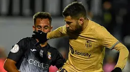 Pemain AD Ceuta Alain Garcia (kiri) berebut bola dengan pemain Barcelona Jordi Alba pada pertandingan sepak bola babak 16 besar Copa del Rey di Stadion Alfonso Murube, Ceuta, Spanyol, 19 Januari 2023. Barcelona mengalahkan AD Ceuta dengan skor 5-0. (JORGE GUERRERO/AFP)