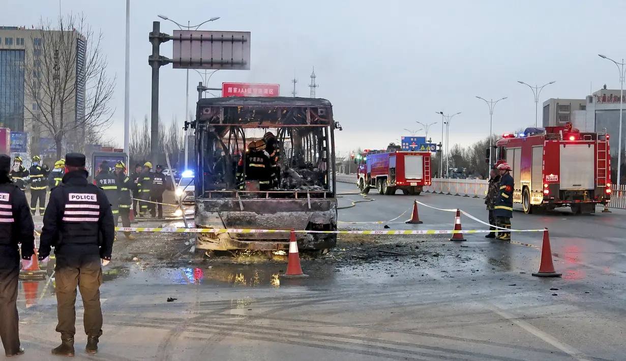 Petugas pemadam kebakaran saat memeriksa isi dalam bus usai hangus terbakar di sebuah jalan di Yinchuan, China, (5/1). 14 orang tewas dan 30 lainnya terluka akibat peristiwa ini. (REUTERS / Stringer)