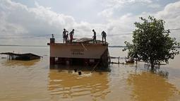 Sejumlah warga berada di atap rumah saat terjebak banjir di Allahabad, India, (21/8). Banjir bandang menerjang sejumlah wilayah di India yang menyebabkan banyak warga yang terjebak. (REUTERS/Jitendra Prakash)