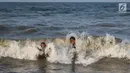 Dua orang bocah bermain ombak di Pantai Randusanga Indah, Brebes, Jawa Tengah, Minggu (2/7). Pantai Randusanga Indah menjadi salah satu destinasi wisata bagi para pemudik yang melewati jalur Pantura. (Liputan6.com/Faizal Fanani)