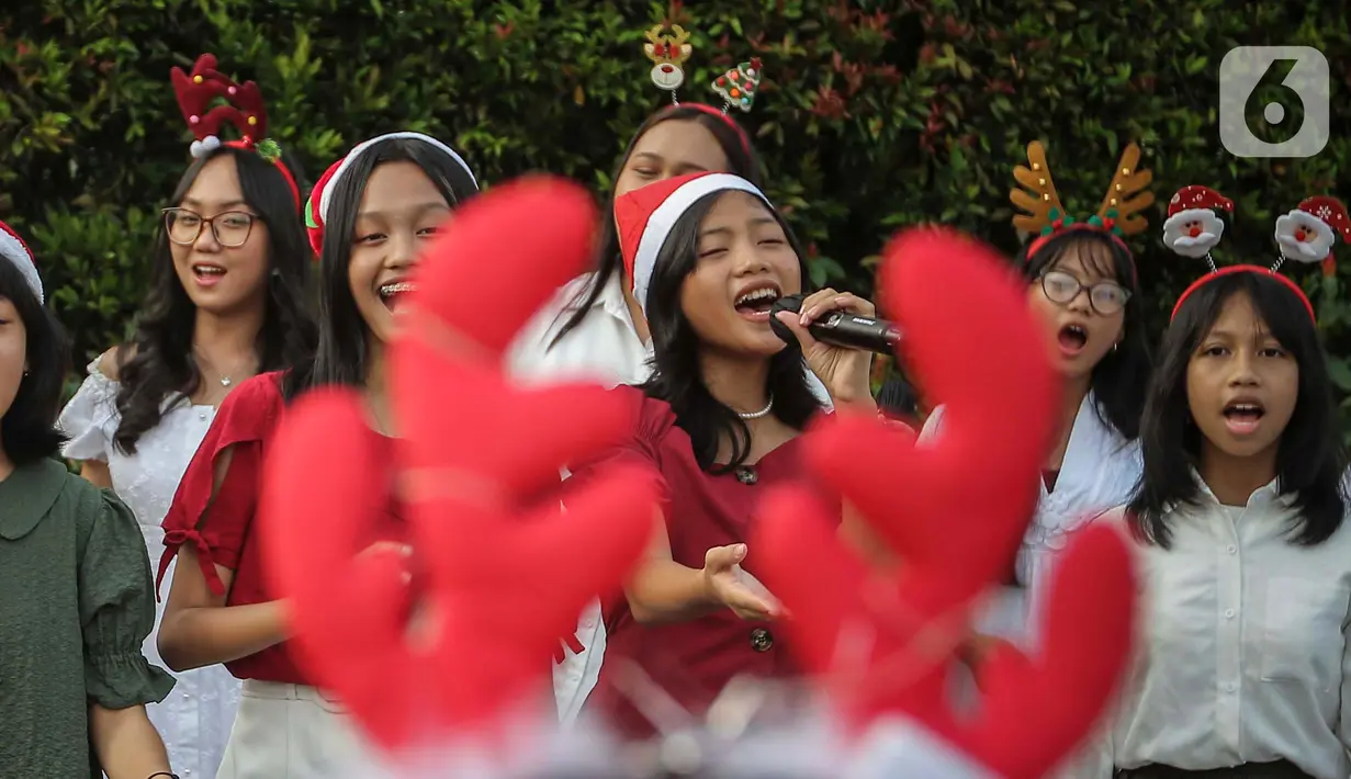 Paduan suara Sekolah Minggu Gereja Toraja Depok saat menyanyikan lagu lagu rohani di Bundaran HI, Jakarta, Jumat (22/12/2023). (Liputan6.com/Angga Yuniar)