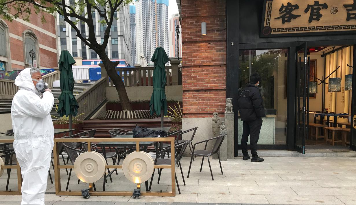 Penjaga toko  mengenakan pakaian pelindung menunggu pelanggan di sebuah jalan ritel di Wuhan di provinsi Hubei, China tengah (30/3/2020). Negara ini memiliki total 81.470 kasus corona yang dikonfirmasi. (AP Photo/Olivia Zhang)