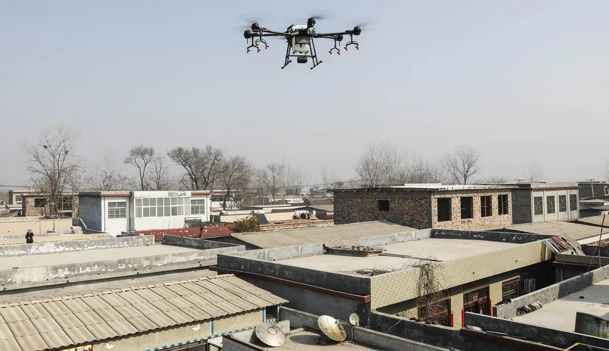 Sebuah drone saat menyemprotkan cairan desinfektan ke sebuah desa di Pingdingshan, Provinsi Henan, China (31/1/2020).  Cara ini digunakan untuk mencegah sekaligus mematikan partikel-partikel virus corona yang menyebar di setiap sudut daerah. (AFP Photo/Str)