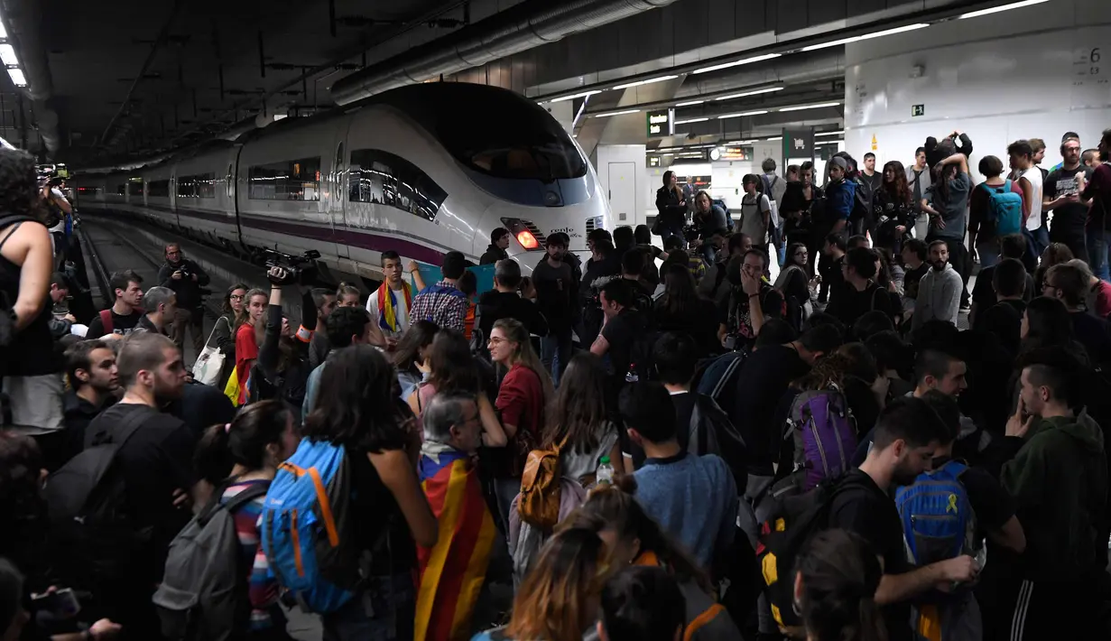 Ratusan massa pro-kemerdekaan Catalonia saat memblokir rel kereta api di Stasiun Sants di Barcelona (8/11). Pengunjuk rasa memblokir jalan dan jalur kereta api setelah para pemimpin separatis ditahan di Madrid. (AFP Photo/Lluis Gene)
