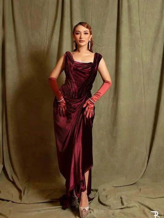 Kali ini, pedangdut yang dikenal karena goyang itiknya yang khas mengenakan gaun merah berbahan beludru yang menonjolkan siluet tubuhnya.  Dress merah dengan detail sequined di bagian dada ini merupakan rancangan desainer kenamaan Indonesia, Hanitio Han. (Instagram/zaskiagotik).