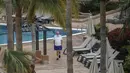 Seorang pria berjalan di samping kolam renang hotel H10 Costa Adeje Palace di La Caleta, di Canary Island of Tenerife, Spanyol, Kamis (27/2/2020). Para tamu hotel tersebut diimbau mengenakan masker saat beraktivitas untuk mencegah wabah virus corona COVID-19. (AP Photo/Joan Mateu)