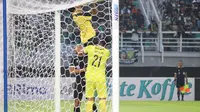Penjaga gawang Madura United, Rendy Oscario menggendong petugas Stadion Gelora Bung Tomo untuk membetulkan gawang. (Bola.com/Wahyu Pratama)