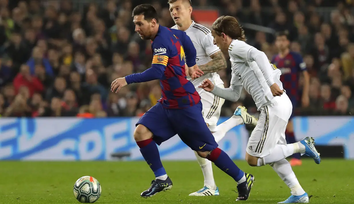 Penyerang Barcelona, Lionel Messi menggiring bola dari kejaran gelandang Real Madrid, Luka Modric pada pertandingan lanjutan La Liga Spanyol di stadion Camp Nou (18/12/2019). Barcelona bermain imbang 0-0 atas Real Madrid. (AP Photo/Emilio Morenatti)