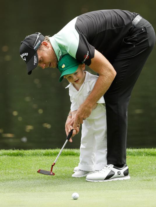 Pegolf Inggris, Danny Willett membantu putranya, Zachariah James memukul bola ketika hari terakhir mengikuti latihan untuk turnamen golf Masters 2018 di Augusta, Georgia, Rabu (4/4). (AP Photo/Matt Slocum)