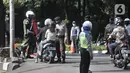 Petugas kepolisian memeriksa identitas pengendara motor yang berpenumpang saat penerapan Pembatasan Sosial Berskala Besar (PSBB) di Jalan Akses UI, Depok, Jawa Barat, Rabu (15/4/2020). PSBB di kota Depok yang resmi berlaku hari ini berlangsung selama 14 hari. (merdeka.com/Iqbal S Nugroho)