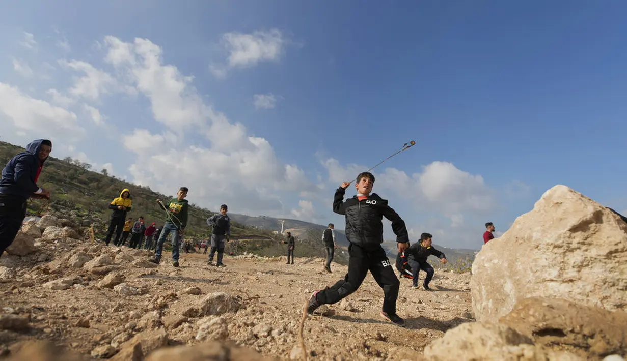 Pengunjuk rasa Palestina menggunakan ketapel saat bentrok melawan tentara Israel di Desa Mughayer, Ramallah, Tepi Barat, Jumat (18/12/2020). Pengunjuk rasa Palestina yang menggunakan ketapel terlibat bentrok dengan pemukim Yahudi yang menggunakan anjing. (AP Photo/Nasser Nasser)