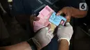 Petugas pos menyalurkan Bantuan Sosial Tunai (BST) kepada warga di kawasan Kebon Jahe, Jakarta Pusat, Rabu (21/7/2021). BST senilai Rp 600 ribu disalurkan untuk dua periode yakni bulan Mei-Juni. (Liputan6.com/Herman Zakharia)