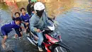 Anak-anak membantu pengendara motor untuk melintasi jalan yang tergenang banjir rob di ruas jalur pantura Semarang-Demak ,Jawa Tengah, Minggu (12 /06/2016). Meski banjir yang cukup tinggi hanya kendaraan besar truk atau bus yang bisa melintas. (Gholib)