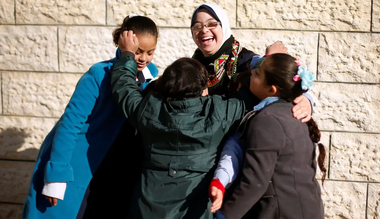 Seorang guru dengan Down Syndrome yang bernama Hiba Al-Sharfa bermain dengan muridnya di sekolah Asosiasi Hak Hidup di Kota Gaza (21/12). Hiba adalah seorang guru yang memeliki “kebutuhan khusus” di Jalur Gaza. (Reuters/Suhaib Salem)