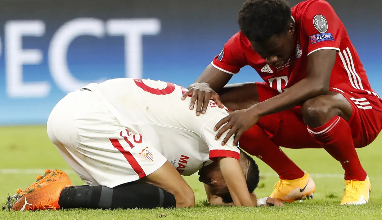 Pemain Bayern Munchen, Alphonso Davies, menenangkan pemain Sevilla, Youssef En-Nesyri, usai pertandingan Piala Super Eropa di Puskas Arena, Budapest, Jumat (25/9/2020) dini hari WIB. Sevilla kalah 1-2 oleh Bayern Munchen. (AFP/Bernadett Szabo/pool)