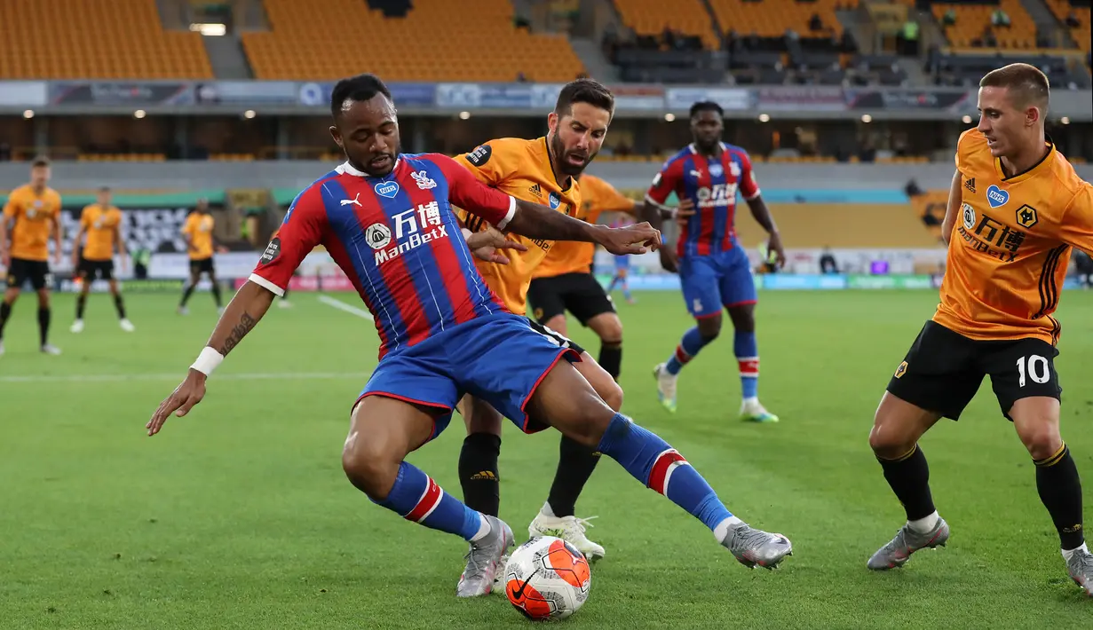 Striker Crystal Palace, Jordan Ayew, berebut bola dengan gelandang Wolverhampton Wanderers, Joao Moutinho, pada laga lanjutan Premier League di Molineux Stadium, Selasa (21/7/2020) dini hari WIB. Wolves menang 2-0 atas Crystal Palace. (AFP/Martin Rickett/pool)