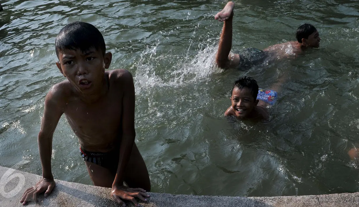 Anak-anak  berenang di kolam air mancur di kawasan Jalan Diponogoro, Jakarta, Jumat (31/7/2015). Minimnya lahan bermain di Ibukota, membuat mereka memanfaatkan kolam air mancur sebagai tempat berenang. (Liputan6/Johan Tallo)