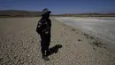 Seorang penjaga kota berdiri di dasar laguna Alalay yang retak dan kering di Cochabamba, Bolivia, Jumat (18/11/2022). Dua laguna, Coña Coña dan Alalay, berada pada level kritis karena kurangnya hujan, penumpukan bahan organik dan penguapan di tengah peningkatan suhu. (AP Photo/Juan Karita)