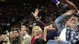 Pemain Los Angeles Lakers, Kobe Bryant melompati deretan penggemar setelah menyelamatkan bola saat bertanding melawan Houston Rockets di Houston pada 20 Desember 2001. Bryant memenangkan lima gelar juara NBA dan peraih medali emas Olimpiade dua kali. (AP Photo/Pat Sullivan)