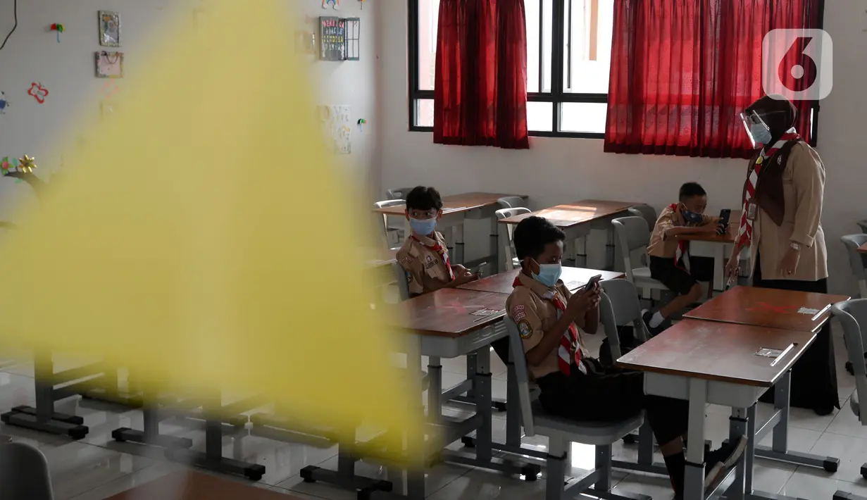 Guru mengajar para murid saat uji coba pembelajaran tatap muka di SDN Malaka Jaya 07 Jakarta, Rabu (9/6/2021). Uji coba pembelajaran tatap muka diikuti dengan jumlah siswa terbatas, menerapkan jaga jarak, dan mengenakan masker untuk menghindari penularan COVID-19. (merdeka.com/Imam Buhori)