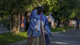 Seorang pria membantu pasangannya mengenakan kostum tradisional saat mereka mengunjungi Kuil Surga pada hari terakhir Hari Nasional China selama seminggu di Beijing (7/10/2021). (AP Photo/Andy Wong)