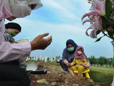 Warga berdoa di depan pusara keluarganya saat ziarah kubur di TPU Srengseng Sawah 2, Jagakarsa, Jakarta Selatan, Senin (17/5/2021). Hari ini seluruh TPU di wilayah DKI dibuka untuk umum dengan menerapkan protokol kesehatan seperti pembatasan pengunjung dan waktu berziarah. (merdeka.com/Arie Basuki)