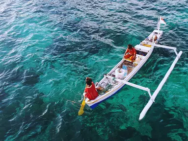 Albin dan Kevin berlayar menggunakan perahu dengan membawa barang dagangan ke Pink Beach, Taman Nasional Komodo, Sabtu, (9/10). Mereka berlayar dari Pulau Komodo menggunakan perahu kecil berbahan bakar solar. (Liputan6.com/Fery Pradolo)