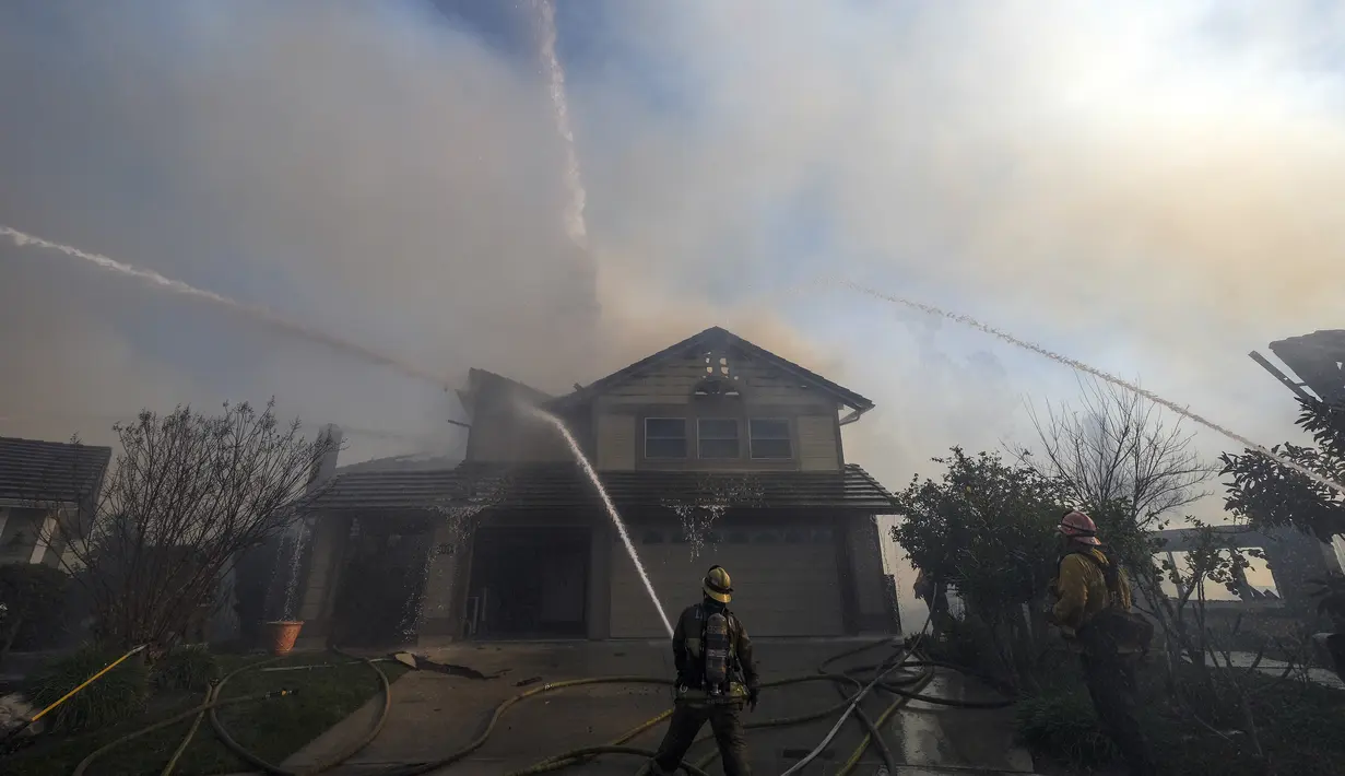 Petugas pemadam kebakaran memadamkan sebuah rumah yang terbakar di Whittier, California (10/2/2022). Setidaknya dua rumah hancur dalam kebakaran semak yang menghitamkan sekitar empat hektar di daerah Whittier. (AP Photo/Ringo H.W. Chiu)