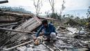Seorang warga menyelamatkan barang-barang miliknya dari rumahnya yang rusak akibat erupsi Gunung Semeru di desa Curah Kobokan di Lumajang, Jawa Timur, Rabu (8/12/2021). Korban meninggal akibat erupsi Gunung Semeru bertambah menjadi 35 orang hingga Rabu pagi. (Juni Kriswanto / AFP)