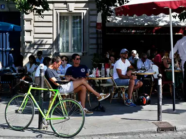 Orang-orang duduk di teras kafe di Paris pada Selasa (2/6/2020). Balai Kota Paris mengizinkan pembukaan area tempat duduk area luar (outdoor) kafe, tetapi di dalam ruangan akan tetap tertutup bagi pelanggan sampai setidaknya 22 Juni mendatang. (AP Photo/Thibault Camus)