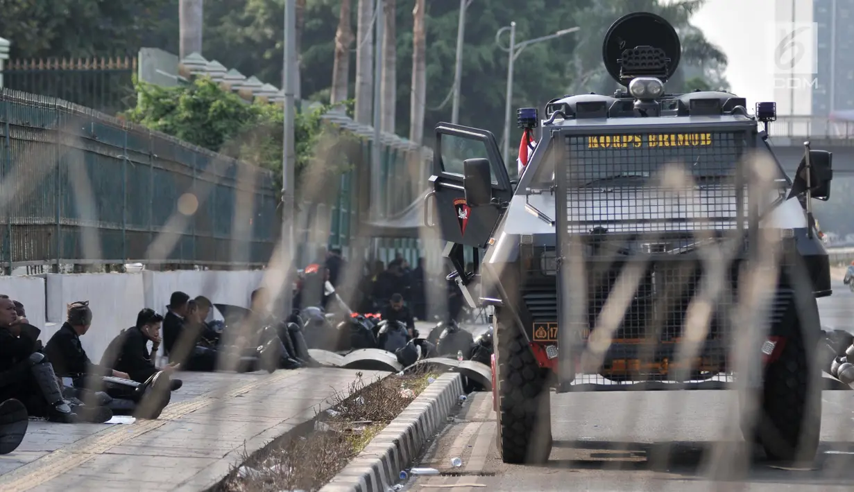 Pollisi beristirahat disamping kendaraan taktis yang menutup akses menuju Gedung DPR RI di Jalan Gatot Subroto, Jakarta, Kamis (26/9/2019). Polisi menutup jalan mulai dari simpang Gerbang Pemuda guna mengantisipasi adanya aksi unjuk rasa susulan. (merdeka.com/Iqbal S Nugoroho)
