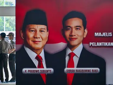 Anggota keamanan gedung parlemen Republik Indonesia berkoordinasi di dekat foto-foto pelantikan presiden dan wakil presiden terpilih 2024-2029, Prabowo Subianto-Gibran Rakabuming Raka, Jakarta pada 18 Oktober 2024. (BAY ISMOYO/AFP)