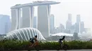Dua pria mengendarai sepeda saat kabut asap menyelimuti kota Singapura (15/9/2019). Akibat kabut asap yang terjadi di kota tersebut membuat Grand Prix Formula 1 di Singapura pekan depan, 20-22 September 2019, terancam batal.  (AFP Photo/Roslan Rahman)