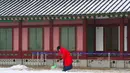 Seorang wanita mengenakan pakaian tradisional Korea "Hanbok" membersihkan salju di Istana Gyeongbok di Seoul, Korea Selatan (15/2). Istana Gyeongbok aslinya didirikan tahun 1394 oleh Jeong do jeon, seorang arsitek.  (AP Photo/Ahn Young-joon)