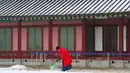 Seorang wanita mengenakan pakaian tradisional Korea "Hanbok" membersihkan salju di Istana Gyeongbok di Seoul, Korea Selatan (15/2). Istana Gyeongbok aslinya didirikan tahun 1394 oleh Jeong do jeon, seorang arsitek.  (AP Photo/Ahn Young-joon)