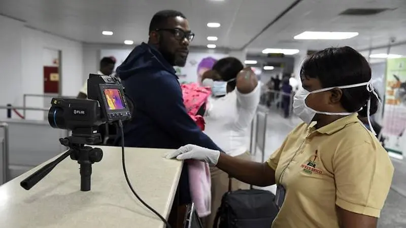 Anggota staf Layanan Kesehatan Port berdiri di sebelah pemindai termal saat penumpang tiba di Bandara Internasional Murtala Mohammed di Lagos, Nigeria, pada 27 Januari 2019.