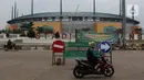 Pengendara motor melintasi jalan depan Stadion Pakansari, Kab Bogor, Jawa Barat, Senin (13/4/2020). Bupati Bogor Ade Yasin menyatakan Pembatasan Sosial Berskala Besar pencegahan penularan virus COVID-19 akan fokus di 11 kecamatan yang masuk kategori zona merah. (Liputan6.com/Helmi Fithriansyah)
