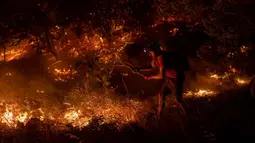 Seorang warga mencoba memadamkan api yang menyebar di Desa Akcayaka, Milas, Provinsi Mugla, Turki, Jumat (6/8/2021). Warga ikut berjuang melawan kebakaran hutan paling mematikan dalam beberapa dekade di Turki. (Yasin AKGUL/AFP)