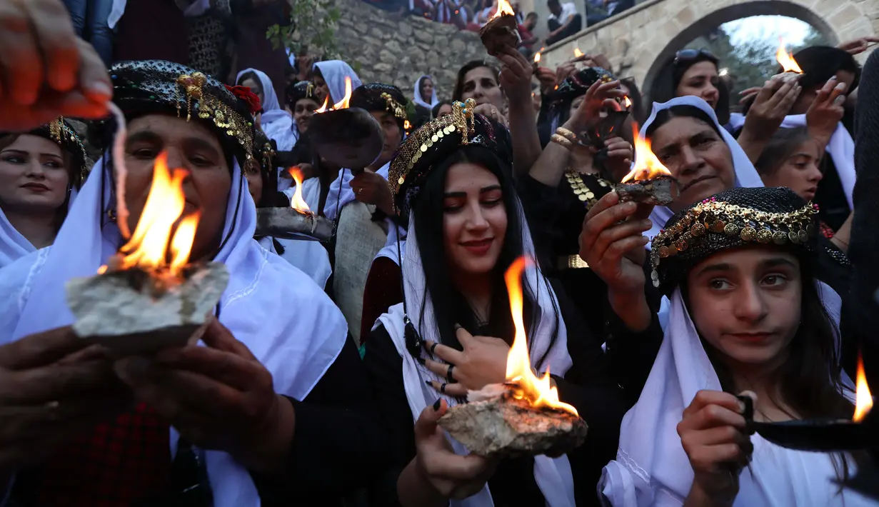 Kelompok Yazidi Irak membawa obor parafin di luar kuil Lalish saat perayaan Tahun Baru Yazidi di lembah dekat Dohuk, Irak (17/4). Agama Yazidi sekilas seperti perpaduan antara Islam, Kristen dan Zoroaster. (AFP/Safin Hamed)